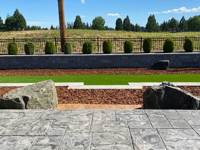 Stamped concrete patio and steps overlooking a stacked stone retaining wall