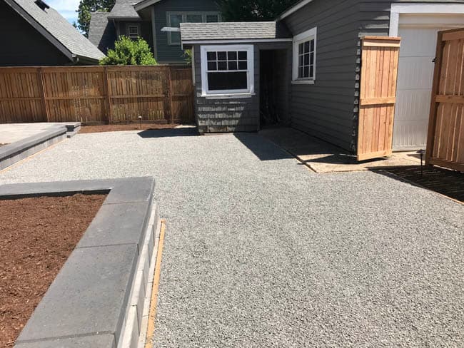 Compacted gravel base with block border prepared for a new residential driveway