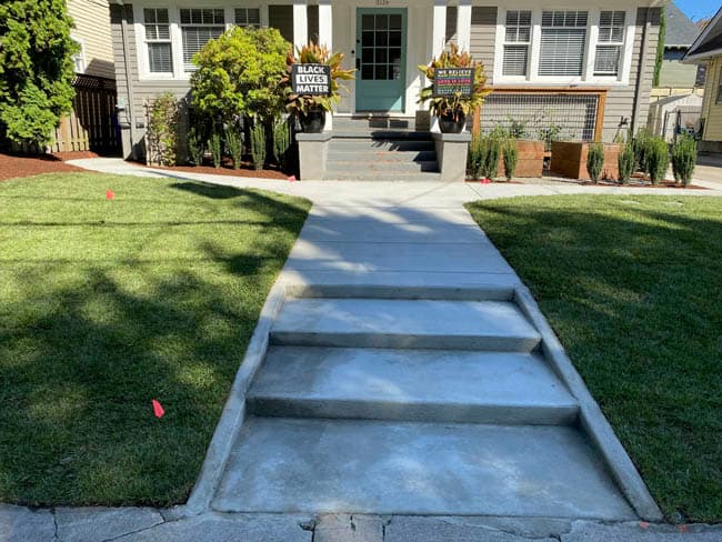 Fresh concrete walkway with stepped grade and clean control joints leading to the front entry