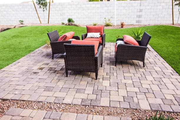 Newly installed paver patio with stylish outdoor furniture and greenery Newly installed paver patio with stylish outdoor furniture and greenery
