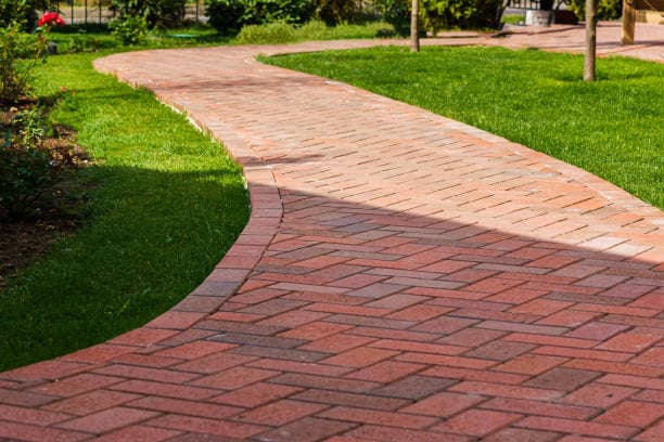 A newly constructed brick walkway with a smooth curve and herringbone pattern A newly constructed brick walkway with a smooth curve and herringbone pattern