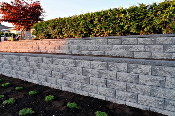Landscaped yard featuring a sturdy retaining wall with decorative touches Landscaped yard featuring a sturdy retaining wall with decorative touches