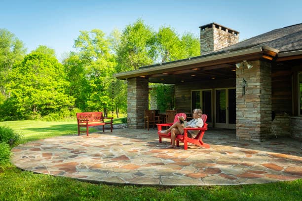 Newly built flagstone patio with red chairs, creating a cozy outdoor space Newly built flagstone patio with red chairs, creating a cozy outdoor space