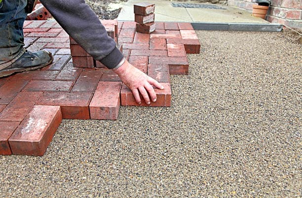 Close-up of a worker carefully placing bricks for a new walkway Close-up of a worker carefully placing bricks for a new walkway