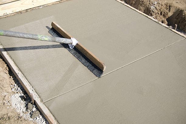 Skilled worker smoothing and texturing a new concrete driveway surface Skilled worker smoothing and texturing a new concrete driveway surface