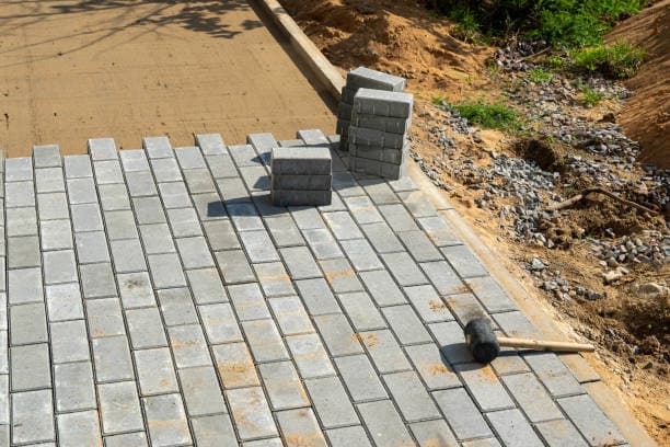 Brick walkway installation in progress with stacked pavers and tools Brick walkway installation in progress with stacked pavers and tools
