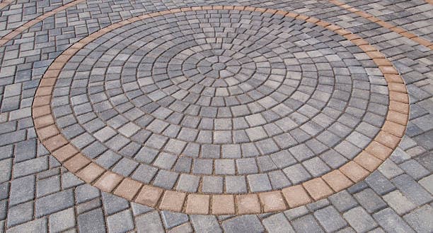 A newly installed patio with a decorative circular pattern of interlocking pavers A newly installed patio with a decorative circular pattern of interlocking pavers