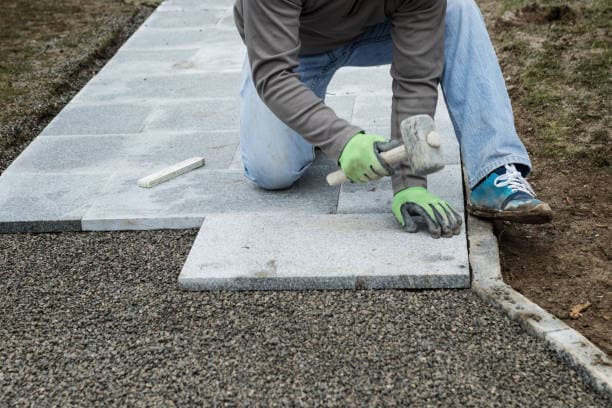 Worker installing stone pavers for a durable and stylish walkway Worker installing stone pavers for a durable and stylish walkway