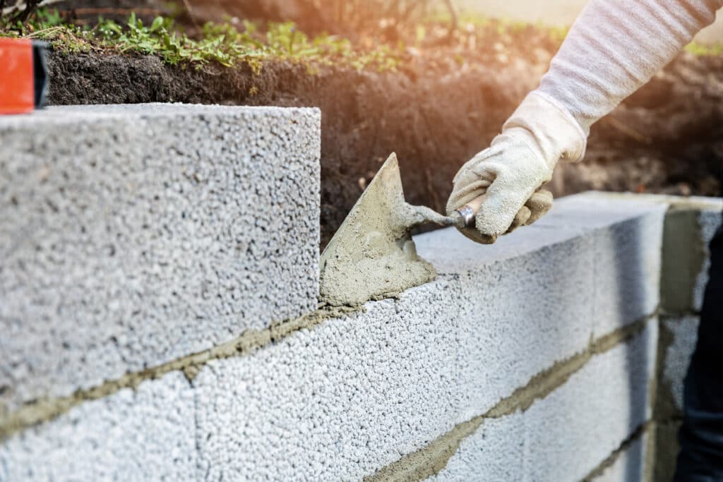 Contractor building concrete block retaining wall with mortar Contractor building concrete block retaining wall with mortar
