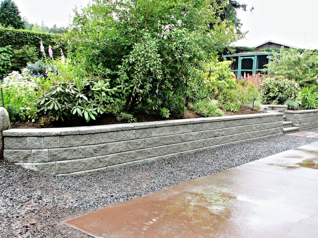Concrete block retaining wall supporting landscaped garden area Concrete block retaining wall supporting landscaped garden area