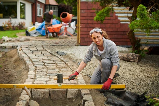 Worker leveling stones for walkway installation with tools Worker leveling stones for walkway installation with tools