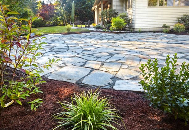 A professionally installed flagstone patio in a landscaped backyard A professionally installed flagstone patio in a landscaped backyard