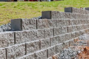 Newly installed stone retaining wall in progress on a construction site Newly installed stone retaining wall in progress on a construction site