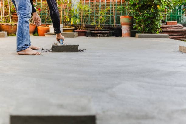 Worker applying final touches to a newly poured concrete patio Worker applying final touches to a newly poured concrete patio