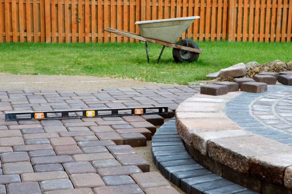 Leveling patio pavers during installation process in a backyard setting Leveling patio pavers during installation process in a backyard setting