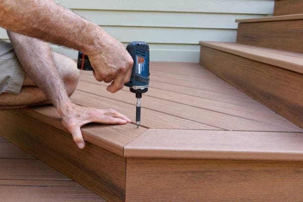 Contractor installing decking on steps with a power drill for assembly Contractor installing decking on steps with a power drill for assembly