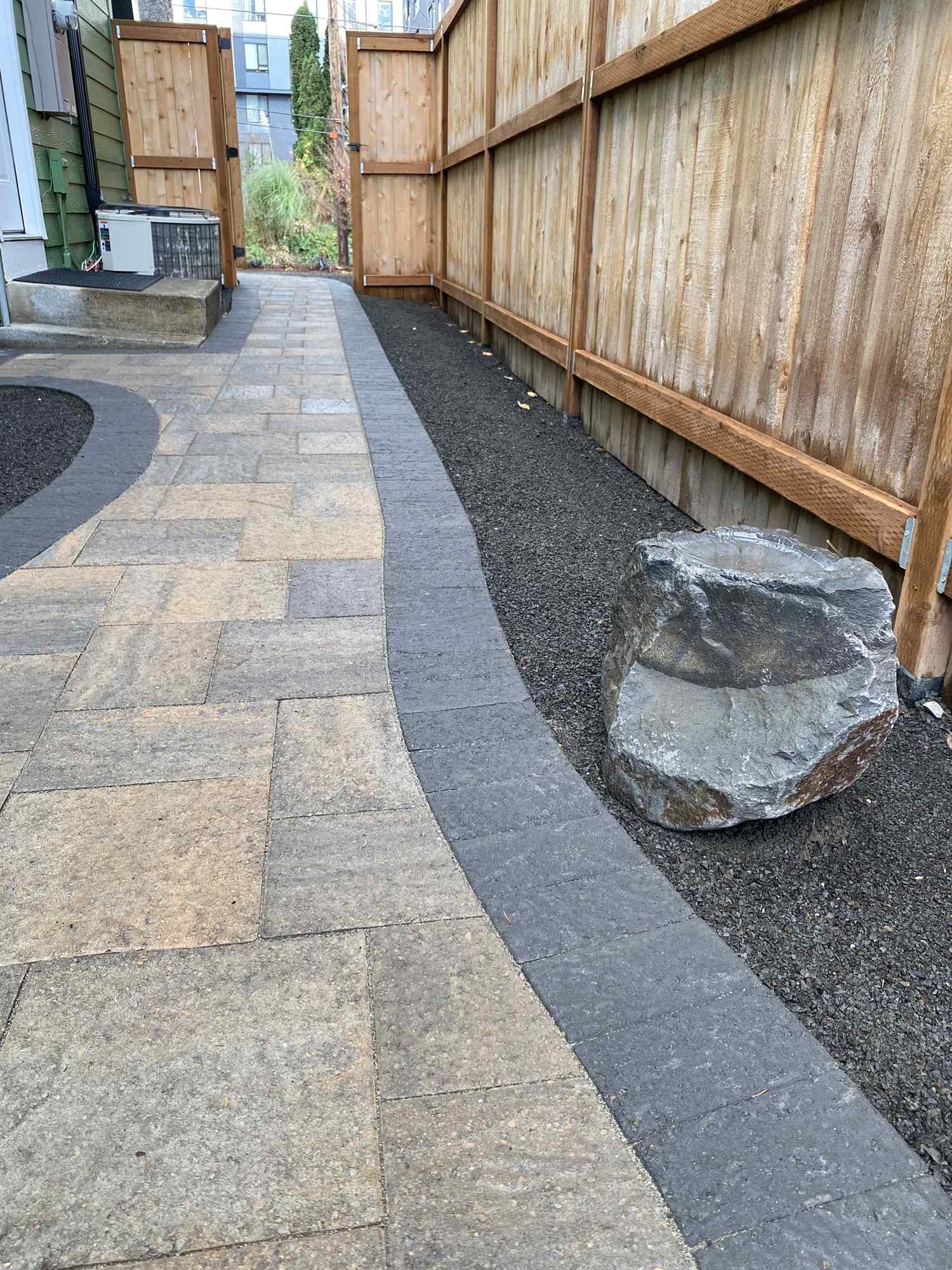 Clean paver pathway with defined planting borders on a maintained property