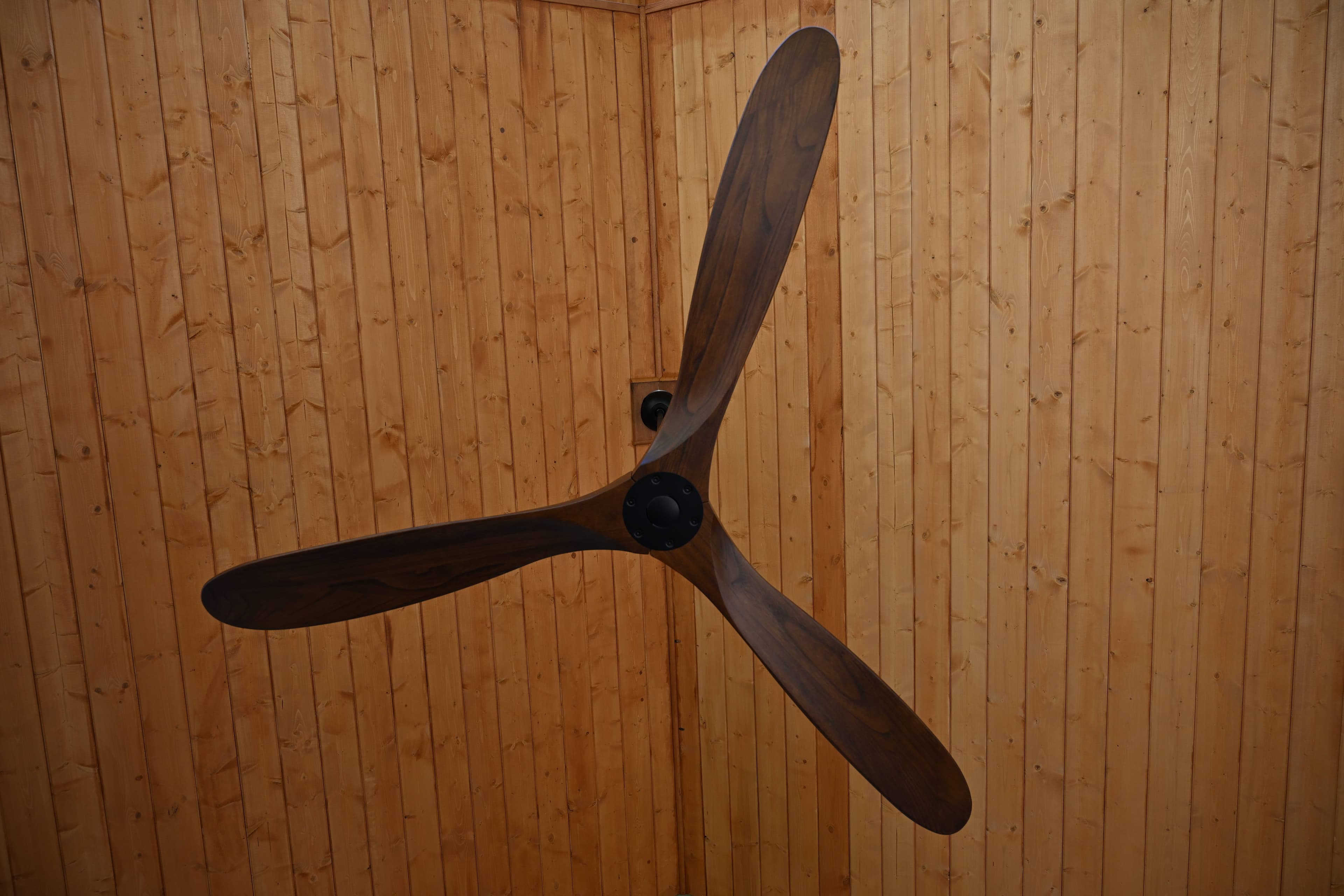 Cedar tongue-and-groove patio cover ceiling with a dark-wood three-blade ceiling fan mounted at center
