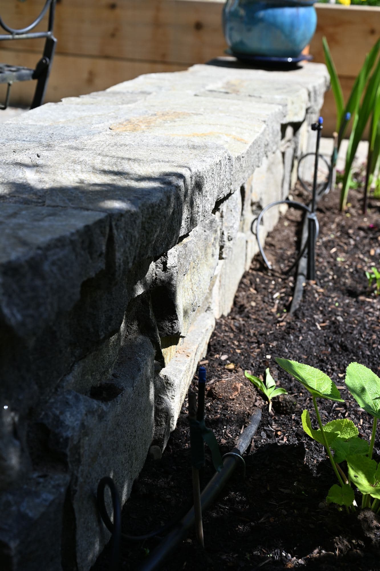 Stacked natural stone wall stabilizing a graded slope above a planting bed