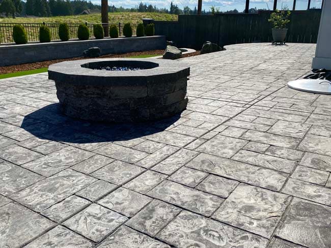 Paver patio with a built-in fire pit anchoring the seating area