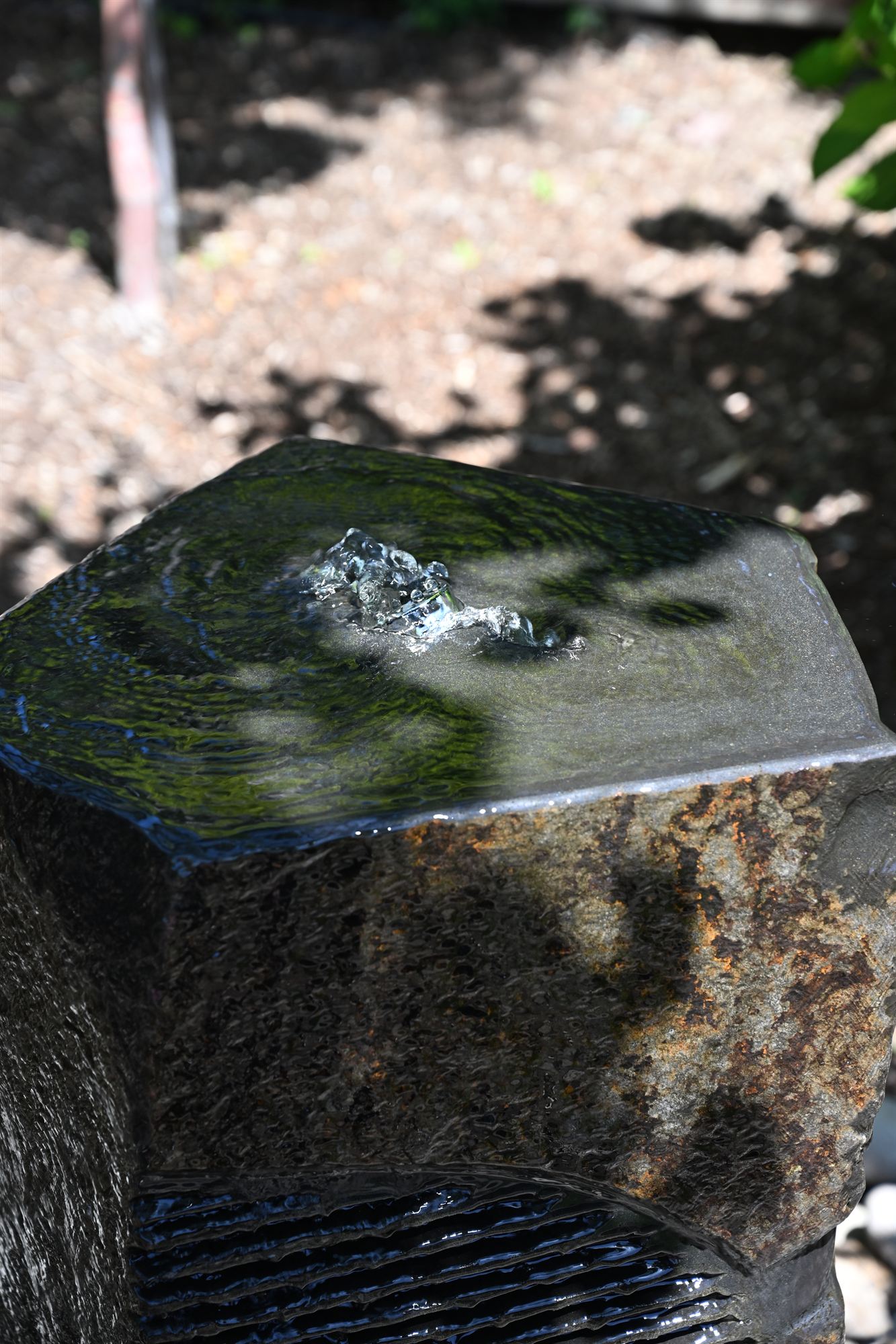 Basalt bubbler fountain set in a river-rock basin