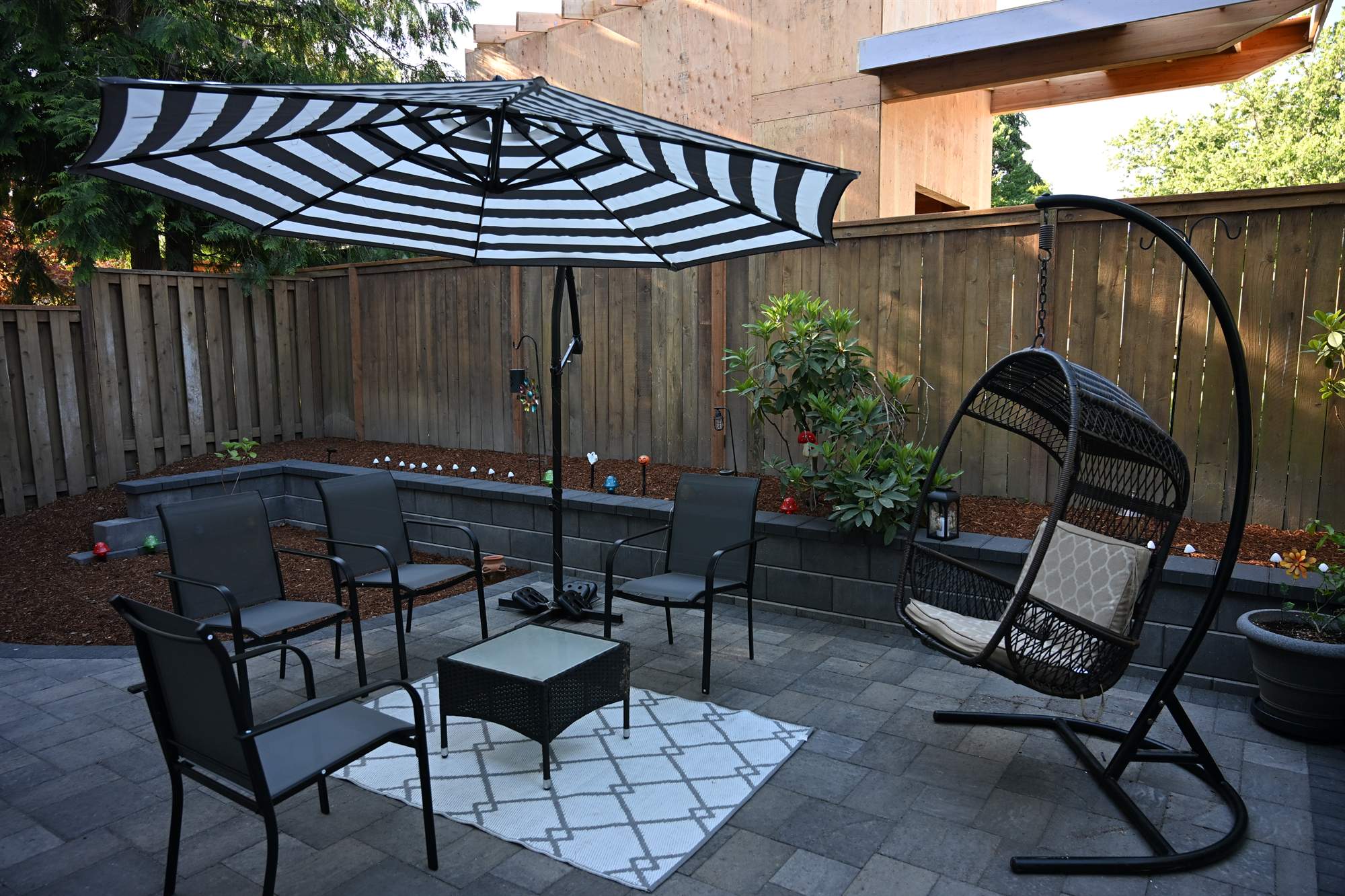 Hanging egg chair on a curved paver patio with fresh plantings